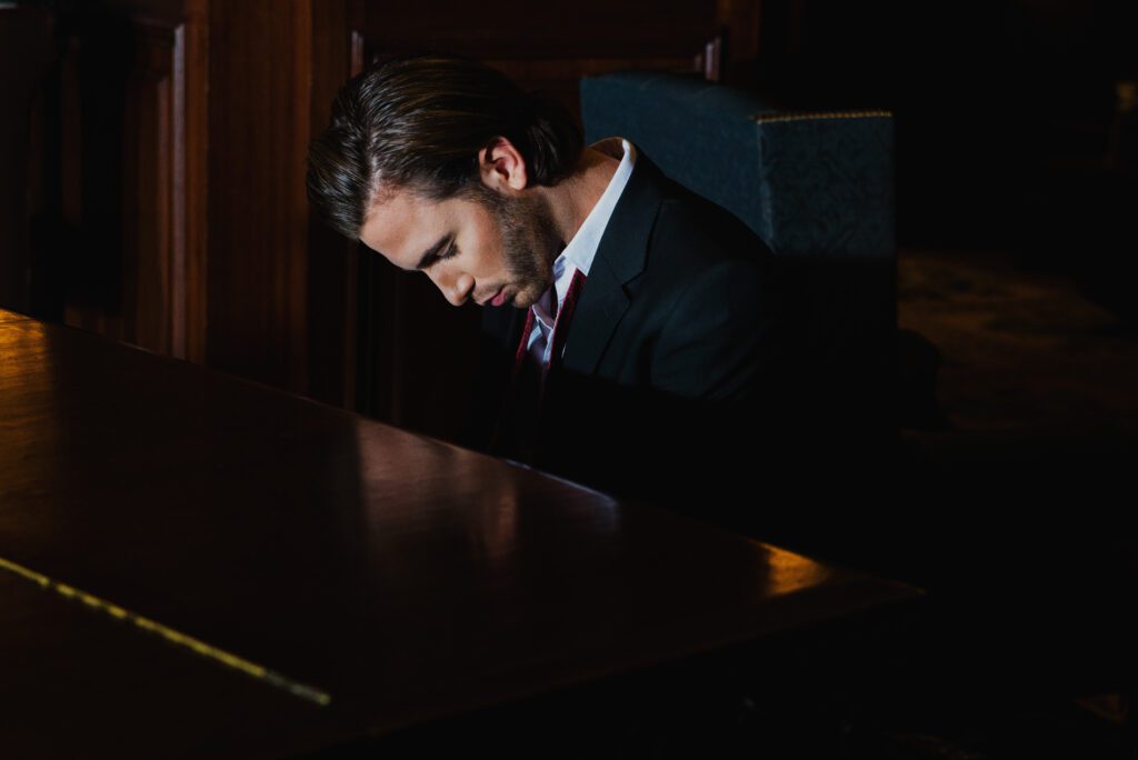 romantic image of a groom playing the piano reminiscent of the handsome bill evans from the 50s